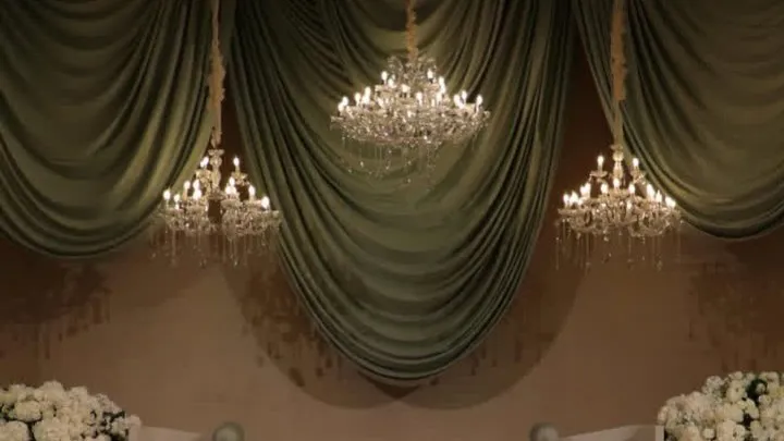 Crystal chandeliers hanging against sage green drapery