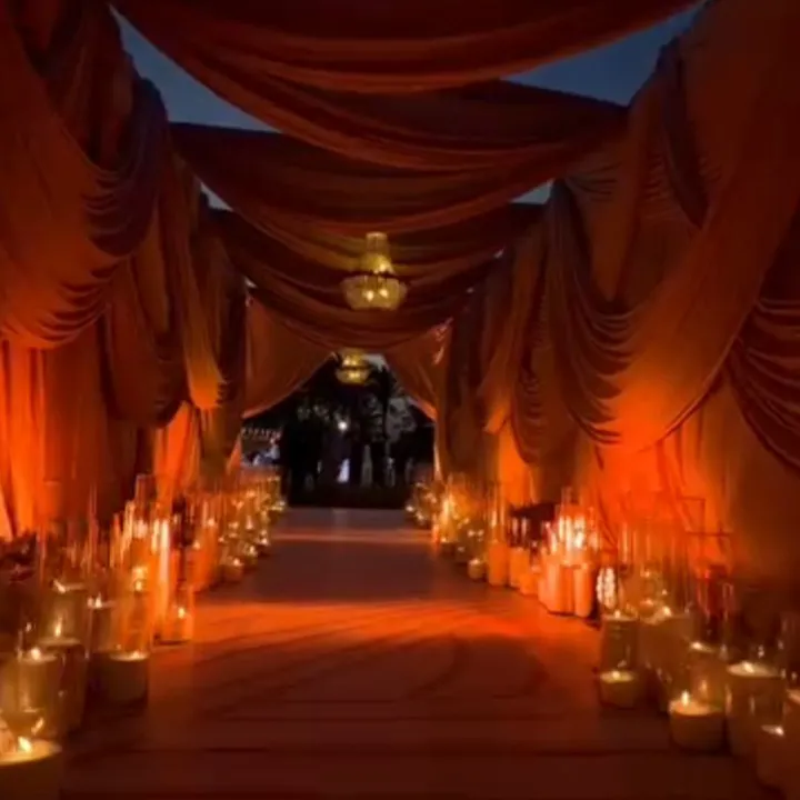Outdoor walkway under amber drapery, lined with candles in glass holders